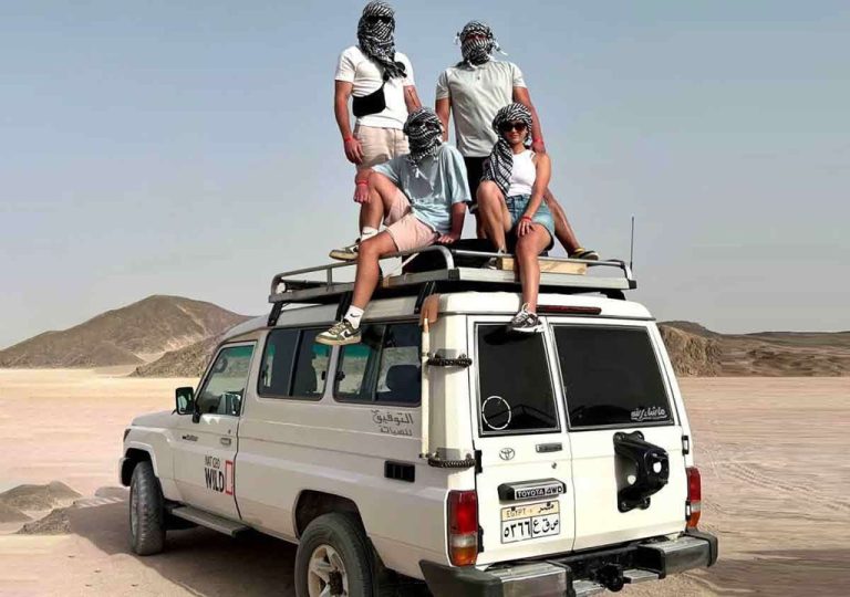 Group of tourists taking photos on a 4x4 safari Jeep during a Super Safari from Makadi